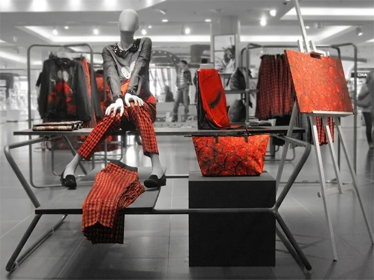 Warenpräsentation auf einer Aktionsfläche Warenpräsentation auf einer Aktionsfläche: Figur in rot-schwarz Kleidung sitzt auf einem Tischgestell, umgeben von passenden Accessoires